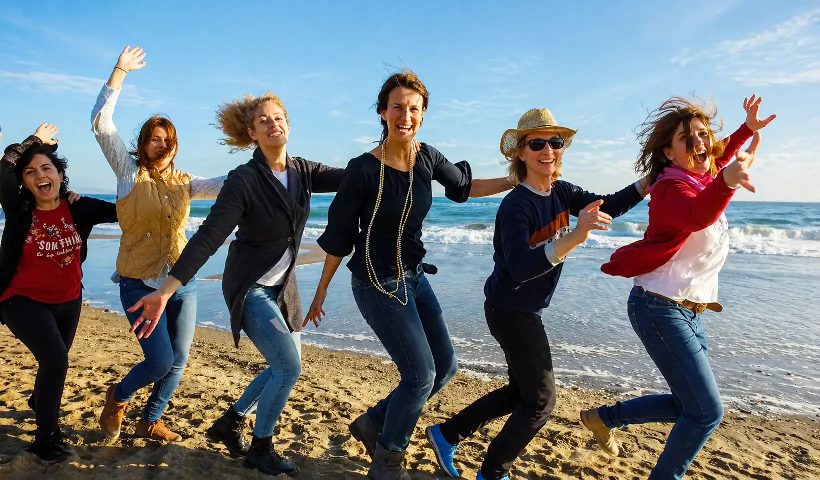 Group of friends dancing on the beach during a Barcelona hen party