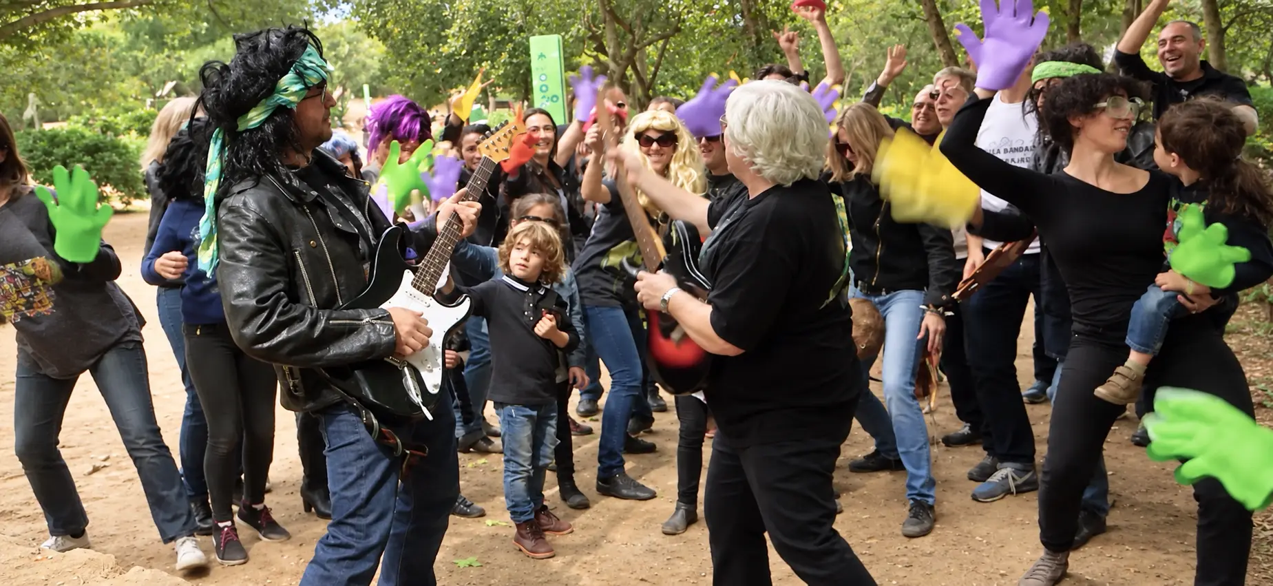 Grupo con pelucas y manos de colores participando en un lipdub de cumpleaños en el bosque